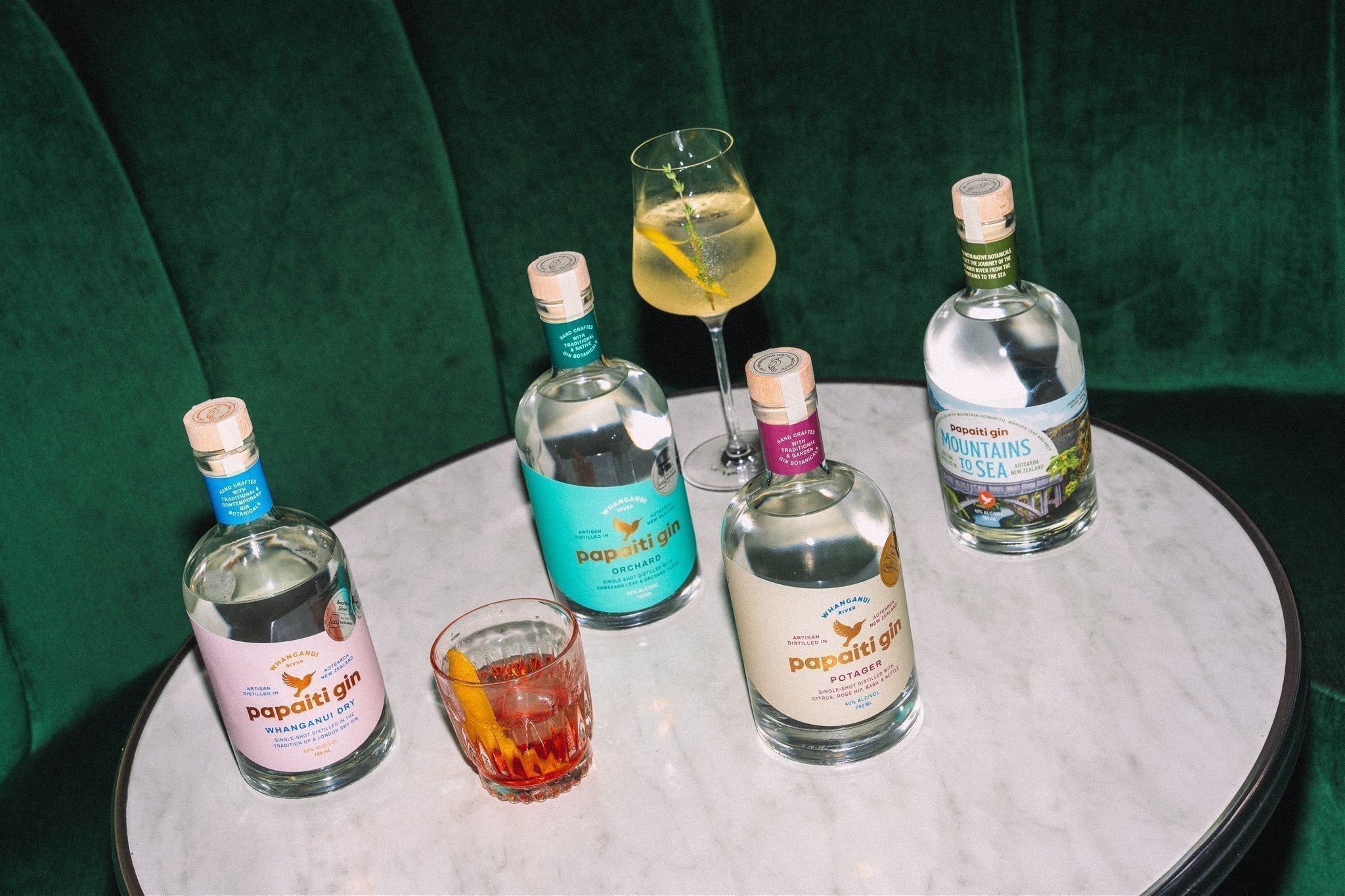 Papaiti Gin bottles and cocktails on a marble table
