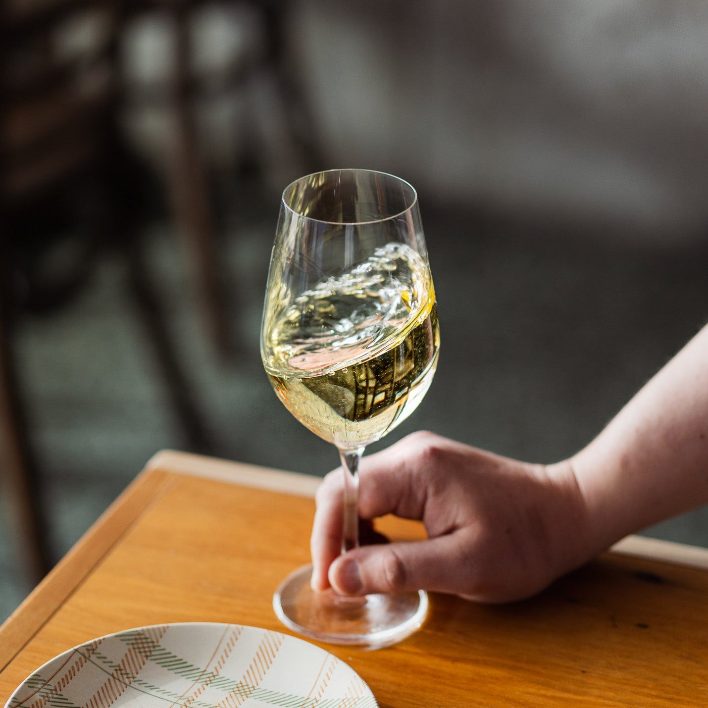 Hand holding a glass on a wooden surface — bright, fresh and beautifully balanced.