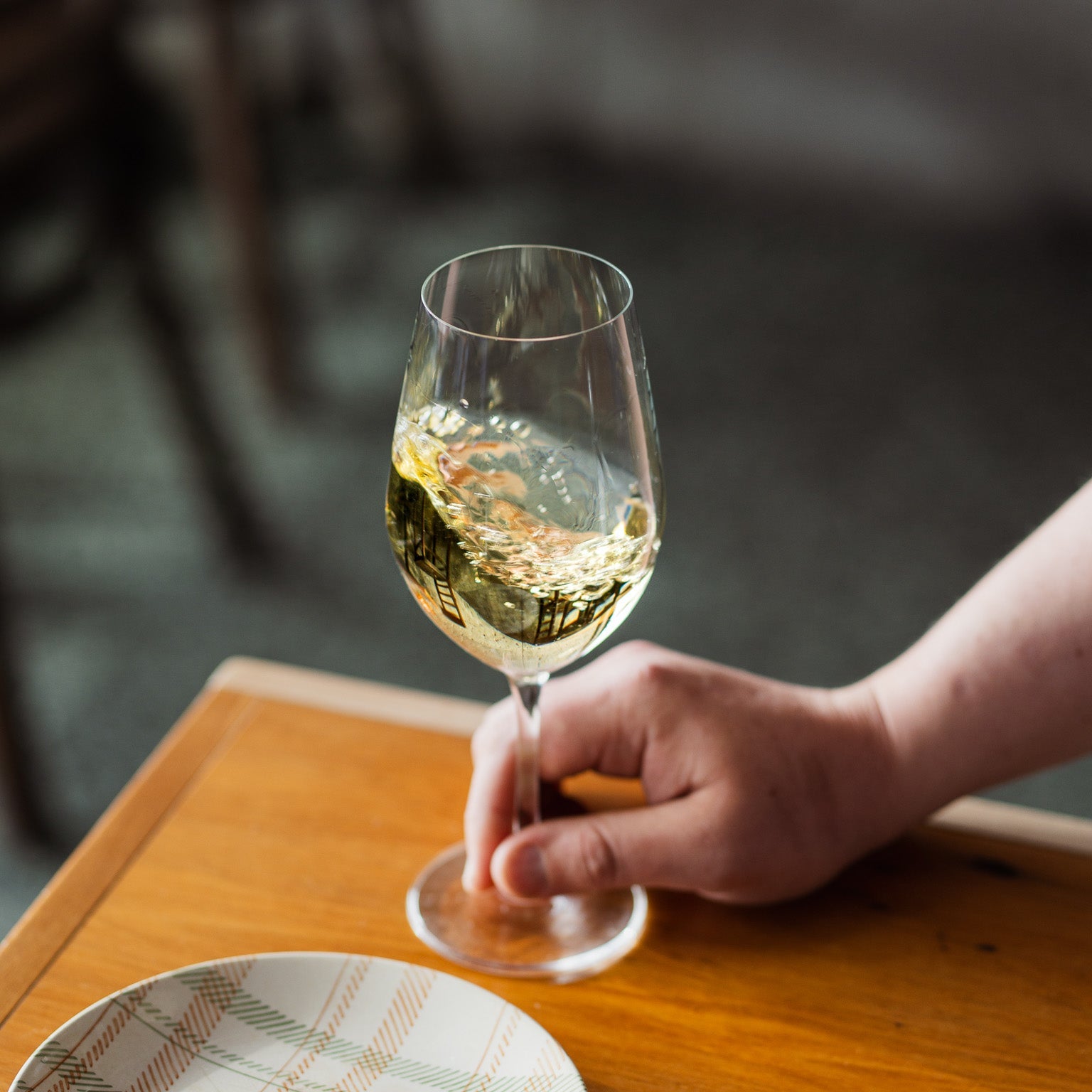 Close-up of a hand lifting a golden glass — elegant and inviting.