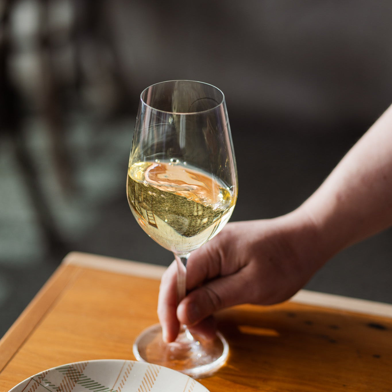 A glass of Hawke's Bay Chardonnay held by hand — silky, golden and ready to enjoy.